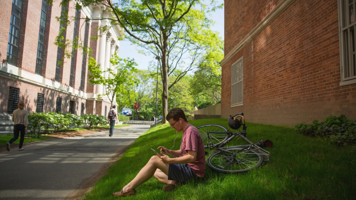 student sitting on grass reading