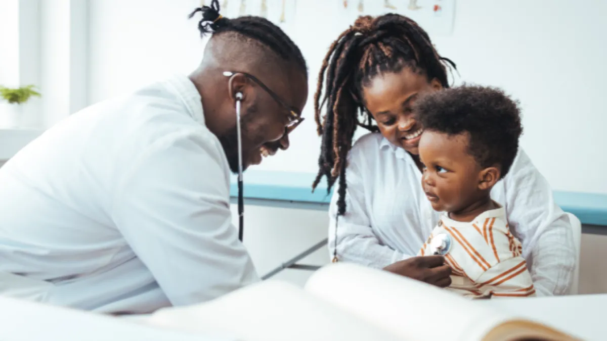 Photo of pediatrician treating young child who is sitting on mother's lap