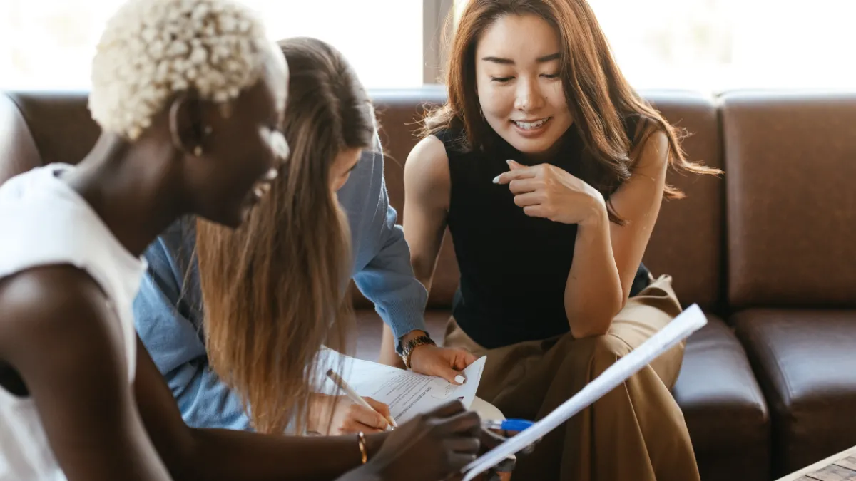 Image of three young professional women discussing paperwork