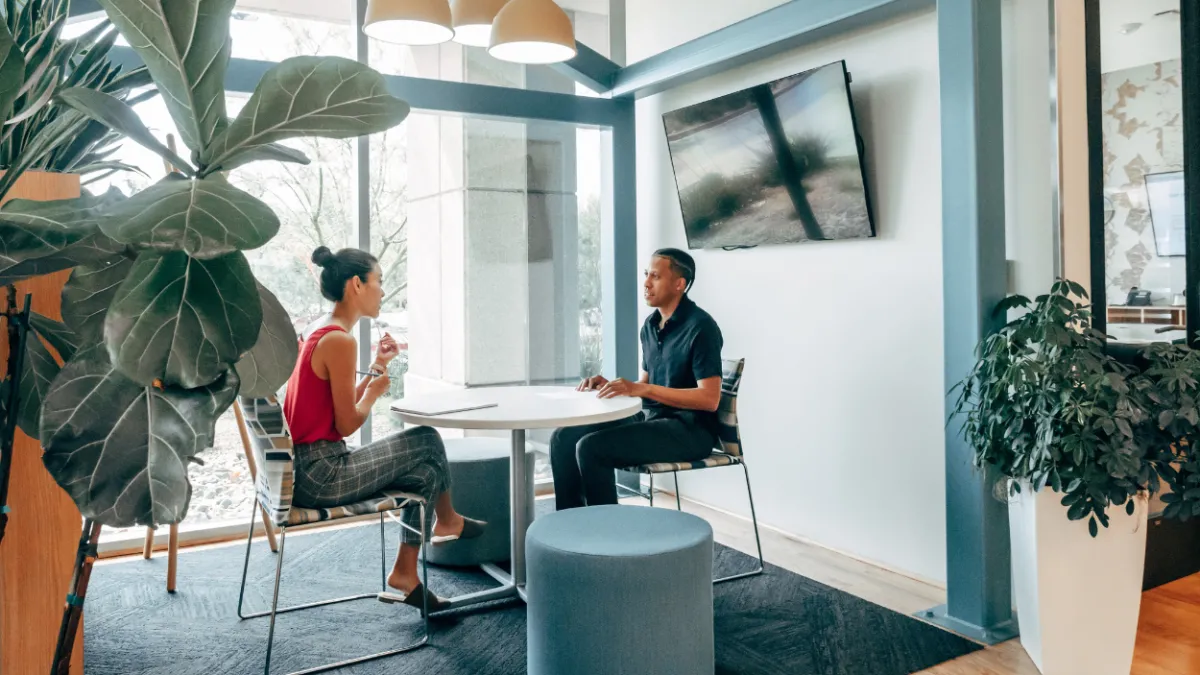 Image of man and woman sitting in an office at a table having a discussion