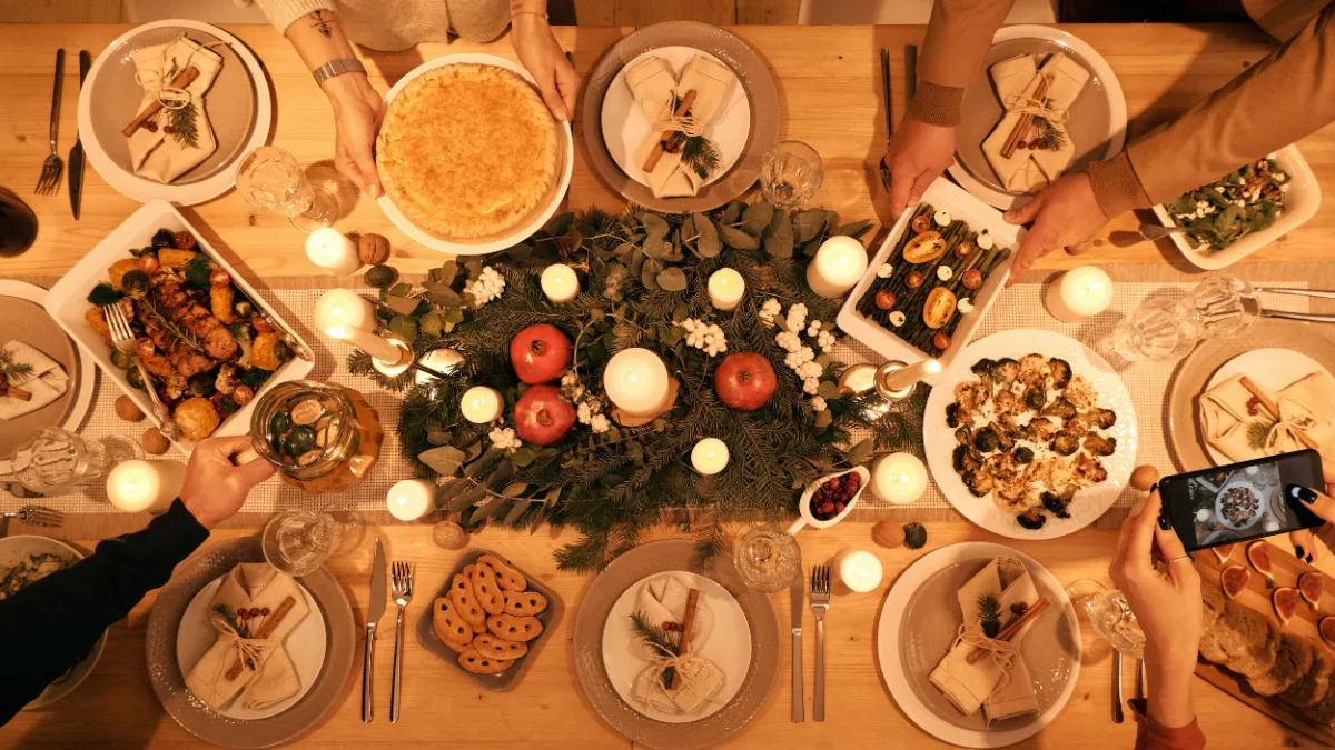 Photo taken from above of a large dining table scattered with holiday dishes and candles