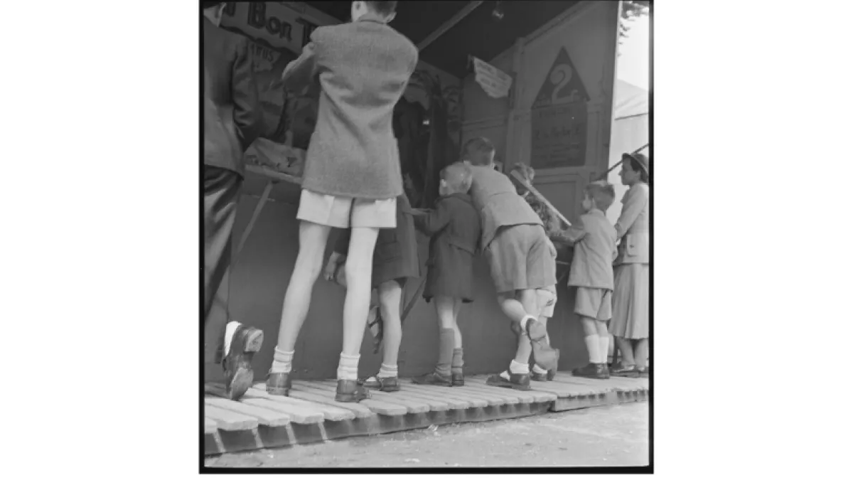 Black and white photo of the backs of children looking at a game.