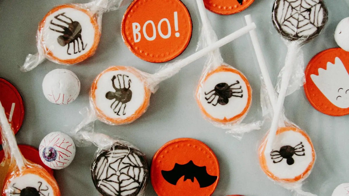 Halloween-themed orange and white lollipops and candy sitting on a white plate
