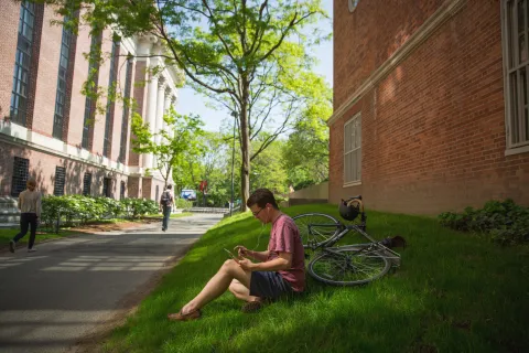 student sitting on grass reading