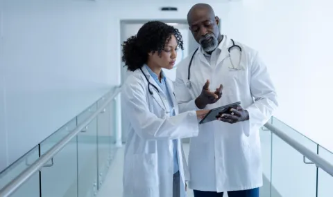 Photo of two doctors, a woman and a man, discussing something over an ipod