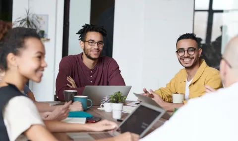 Photo of two young professional men sitting at a table in a meeting