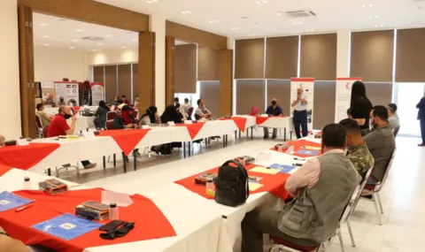 photo of people in a meeting space sitting at long tables listening to a lecture