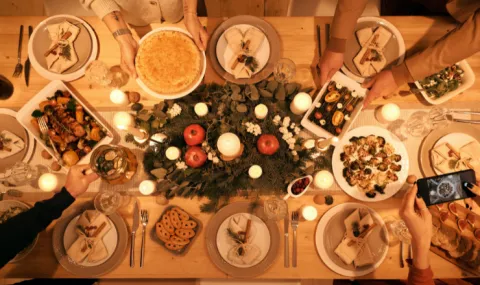 Photo taken from above of a large dining table covered with holiday food and a centerpiece with candles.