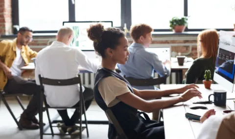 Photo of woman in an open office setting working at her computer