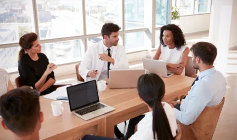 An image of business people sitting around a conference table in discussion